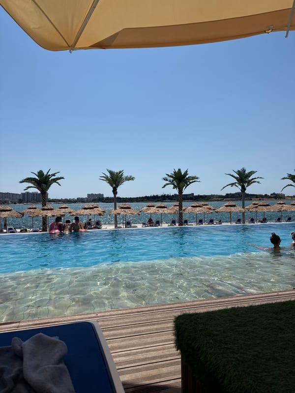 Infinity pool and beach lounges at a sunny coastal resort