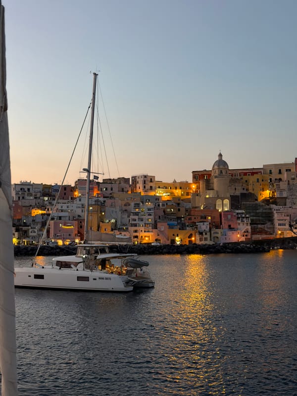 White sailboat docks at Procida harbor during dusk