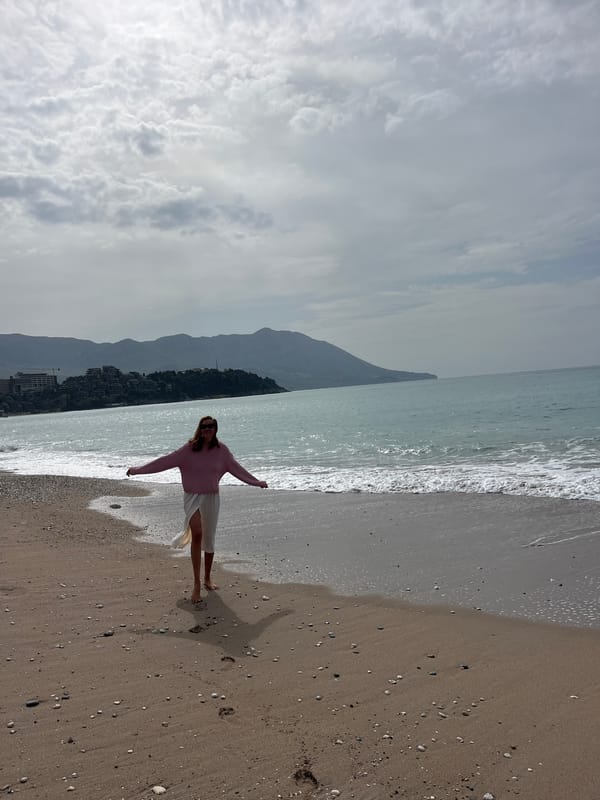 Woman spreads arms on Budva beach overlooking Adriatic Sea