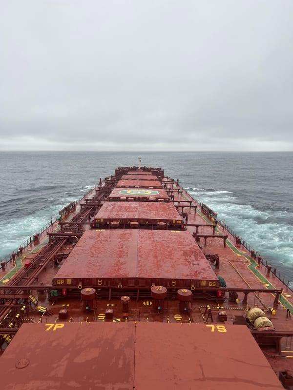 Cargo ship navigates rough gray seas under heavy overcast
