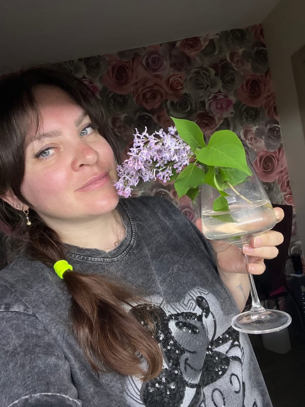 Person holds wine glass with lilac flowers in Noviy, Russia