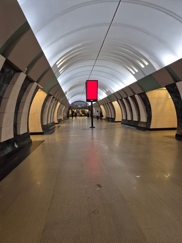 Subway platform with curved ceiling and red digital ad screen