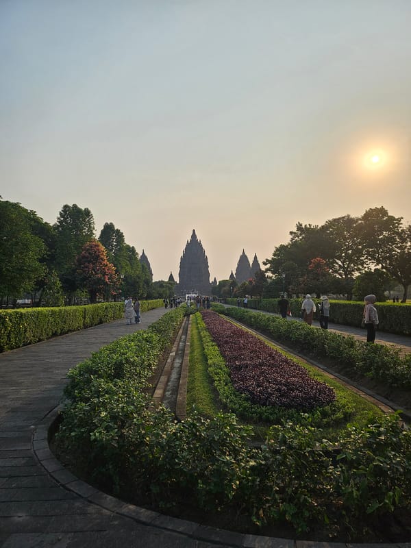 Prambanan Temple at sunset, bathed in hazy golden light.
