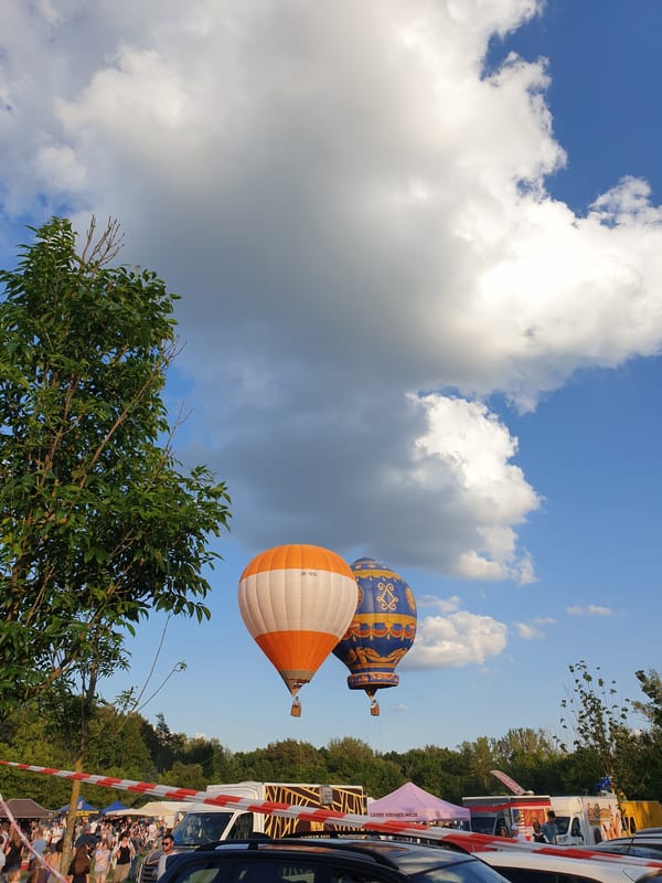 Hot air balloons spotted at outdoor event under cloudy skies