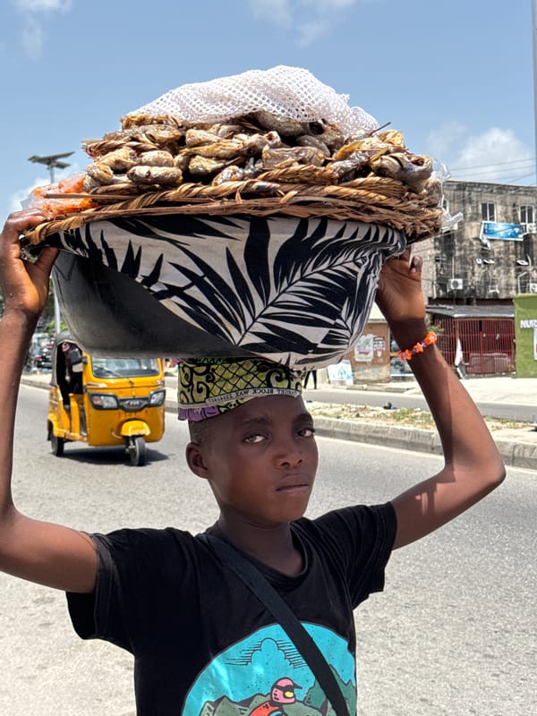 Street vendors carry goods through Ado, Nigeria