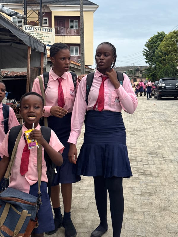 School children gather on street near business in Ado
