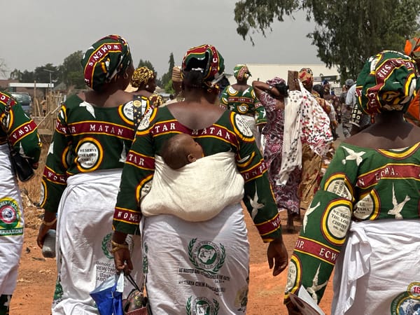 Groups in traditional dress walk village streets