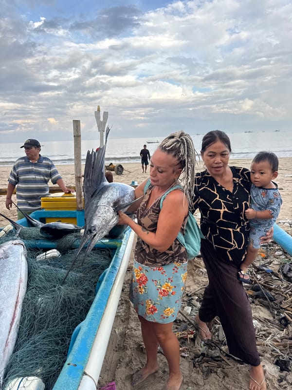 Woman examines large marlin catch on Kuta beach