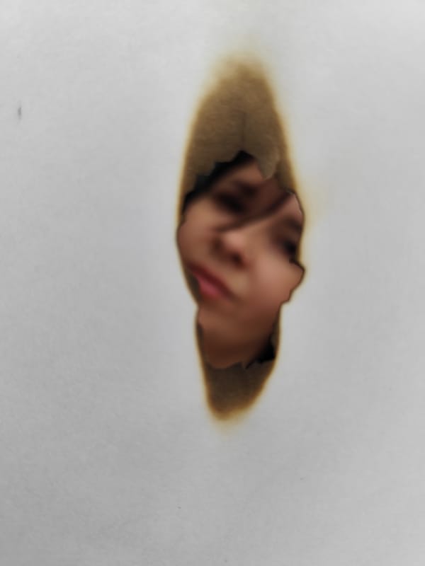 Face glimpsed through burnt hole in paper, Foki Russia