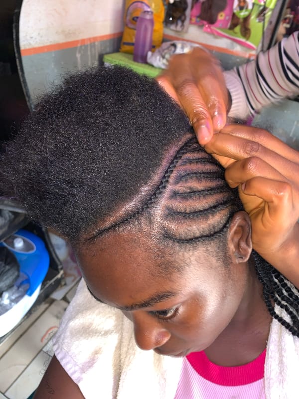 Woman gets cornrow braids at Nigerian salon