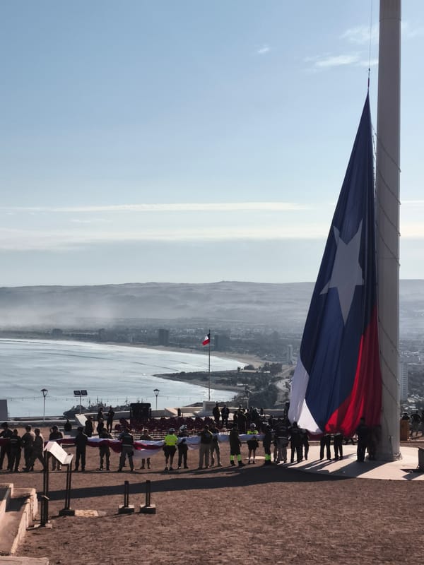 Uniformed personnel gather with flags on Arica hillside