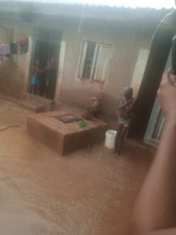 Flooding forces residents to wade through brown water near buildings