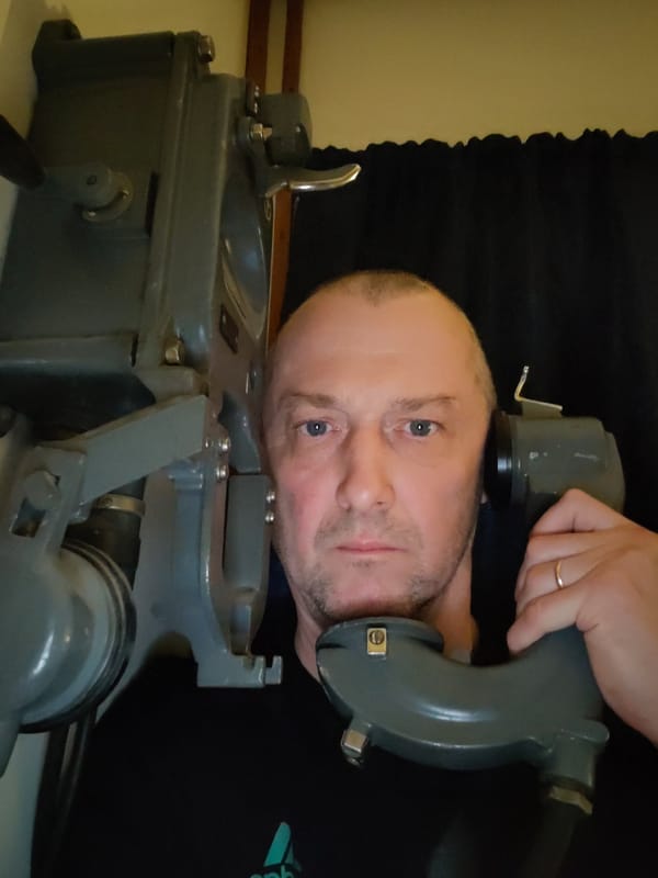 Man photographs vintage equipment aboard ship during evening hours