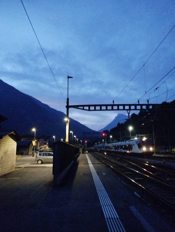 Alpine town at dusk: trains, mountains, and Coop signs
