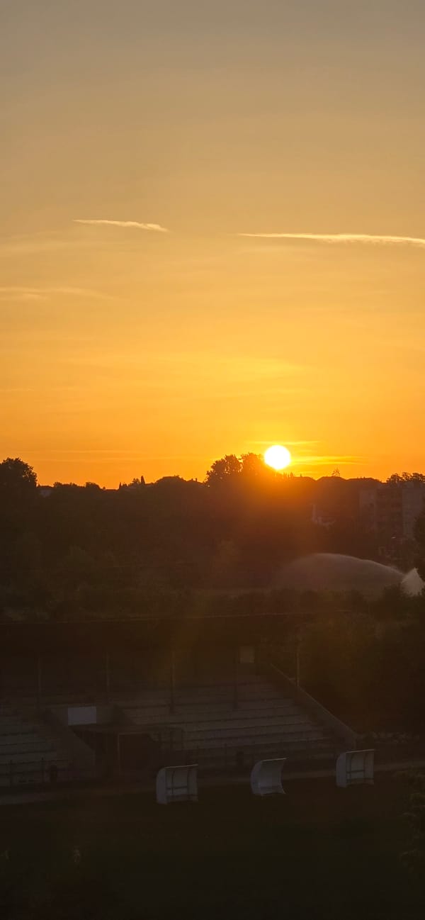 Orange sunset over a city skyline and rugby field