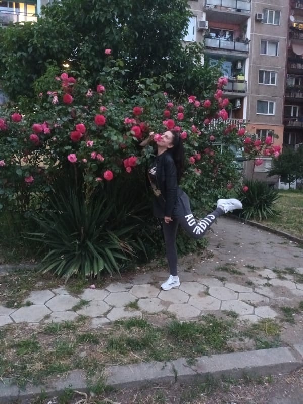 Woman performs athletic pose in Adidas gear near flowers