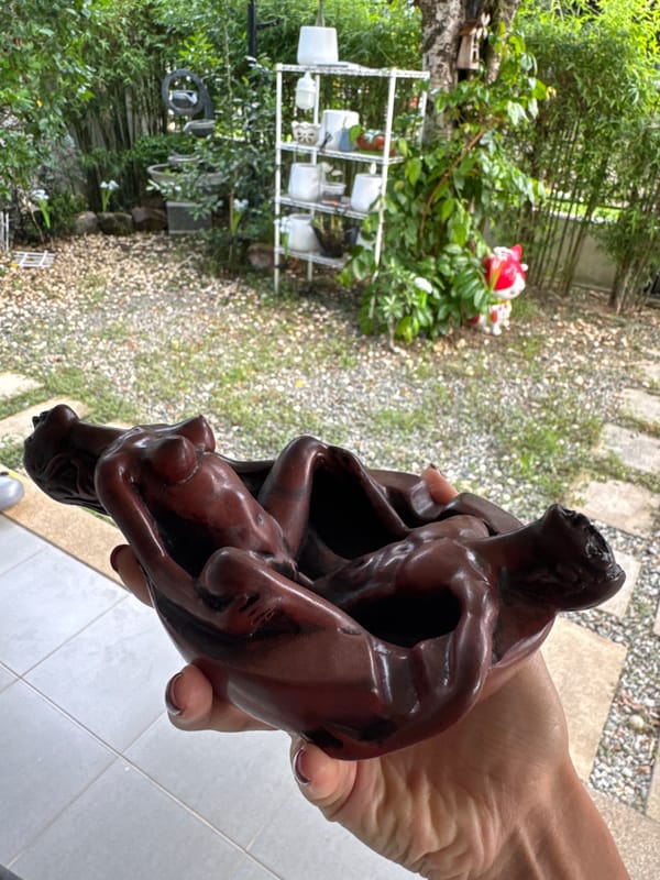 Wooden sculpture of entwined figures displayed in Chalong garden