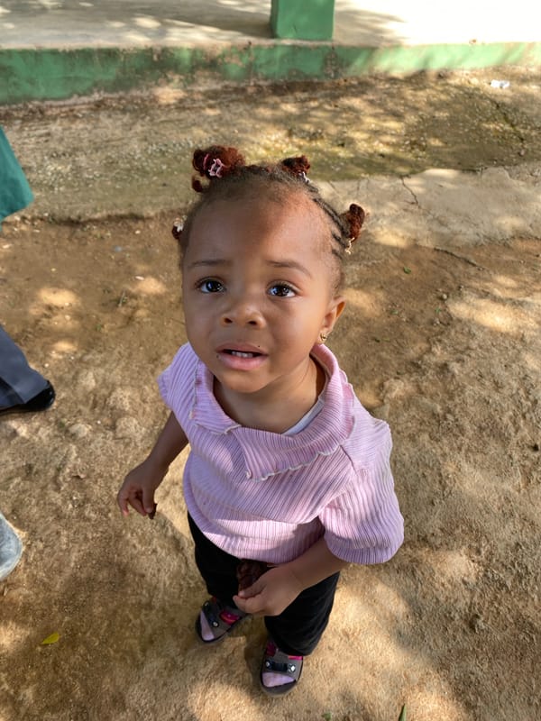 Toddler plays outdoors with caregiver in Nigerian community