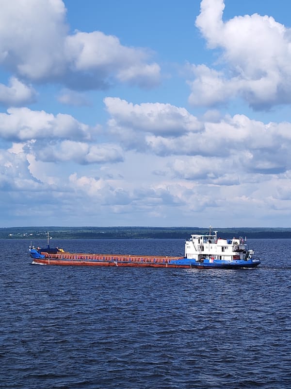 Cargo ships crossing open water on a hazy, sun-lit day