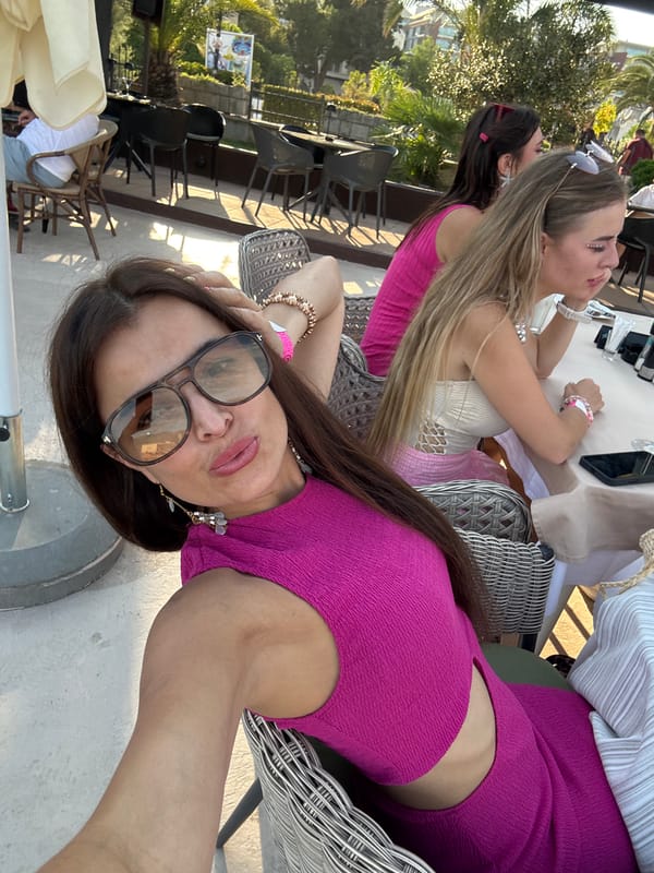 Bright pink outfit and aviator shades, posing outdoors
