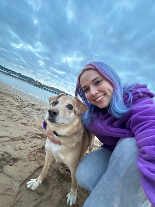 Woman and dog enjoy sunset playtime at Gijón beach