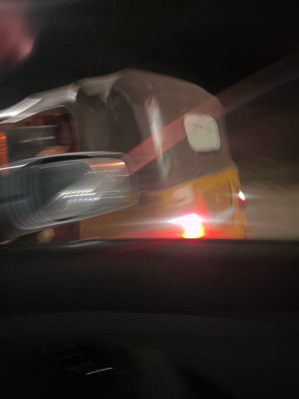 Yellow tricycle captured in motion during nighttime in Abuja