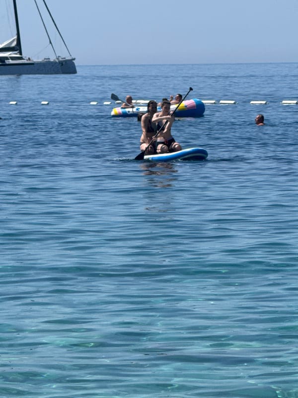 Paddleboarding and swimming on a calm, sunny coastal morning