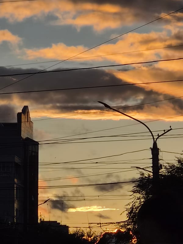 Modern architecture in silhouette against a dramatic sunset sky