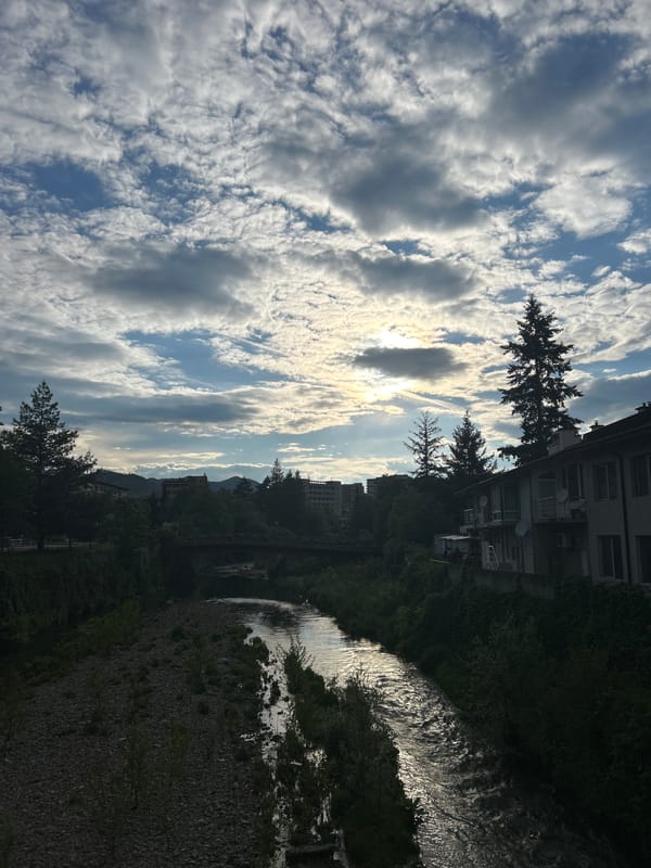 Sunlit stream flows through Zlatograd, Bulgaria under cloudy skies