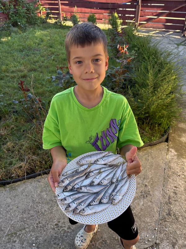Boy displays fresh catch on plate in Plastunka yard