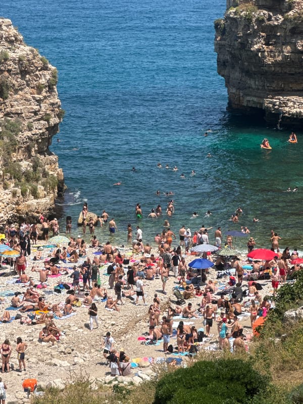 Summer crowds pack Polignano a Mare beach cove