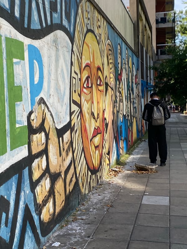 Colorful street mural with faces and fist observed in Buenos Aires
