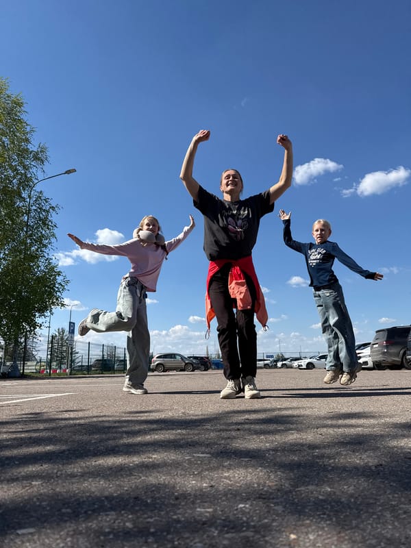 Three people pose and dance at Ufa Airport parking lot