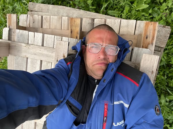 Man rests on wooden pallet outdoors in Topoli