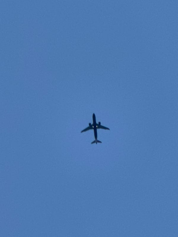 Planes and a crescent moon cross a clear London sky