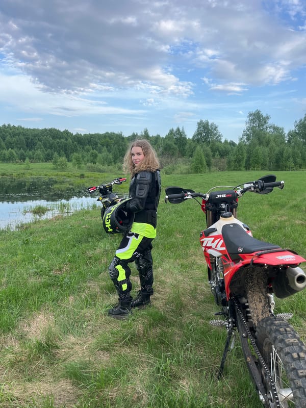 Motocross rider pauses by water with dirt bikes in Russia