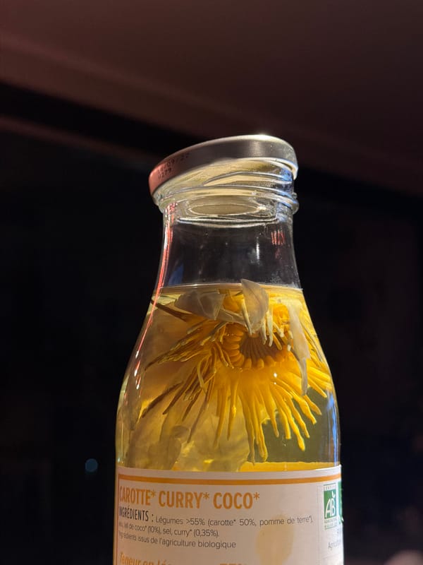Flower preserved in yellow liquid inside a labeled glass bottle