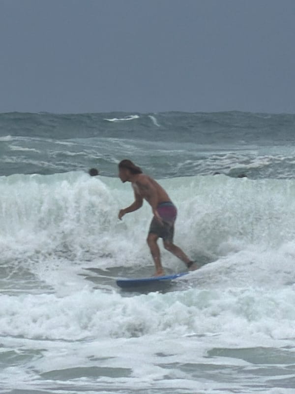 Surfer rides waves near Tel Aviv breakwater amid choppy conditions