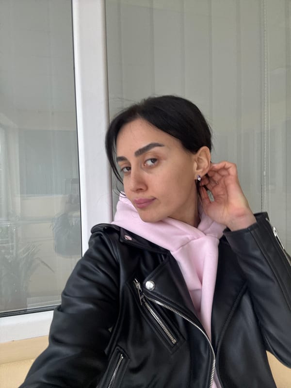 Woman in leather jacket observed near window in Tbilisi