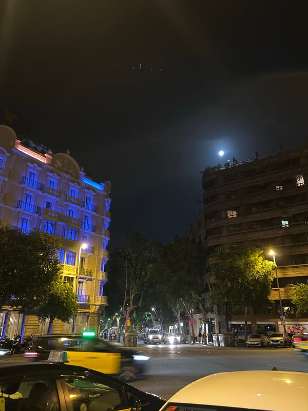 Full moon illuminates Barcelona street scene with parked taxis