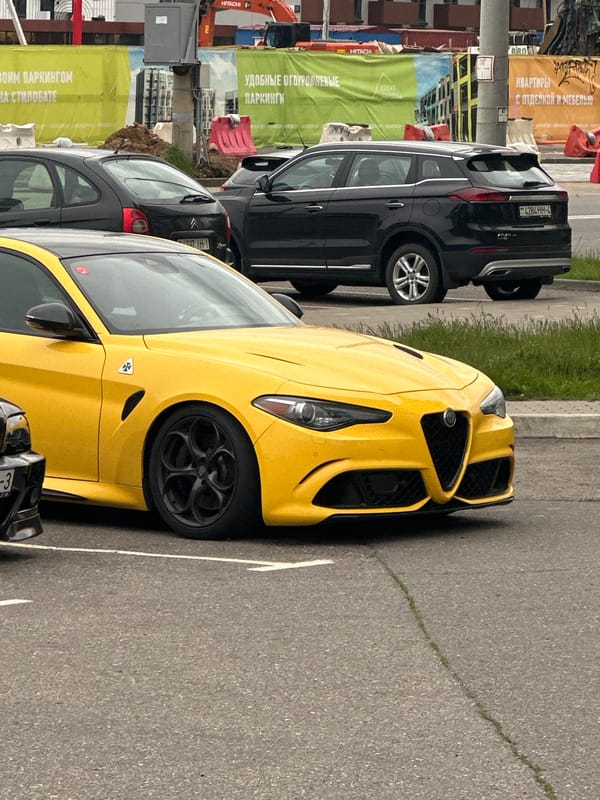 Vehicles including yellow Alfa Romeo parked in Belarus village