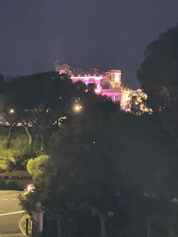 Woman enjoys orange drink in illuminated Grimaud evening scene