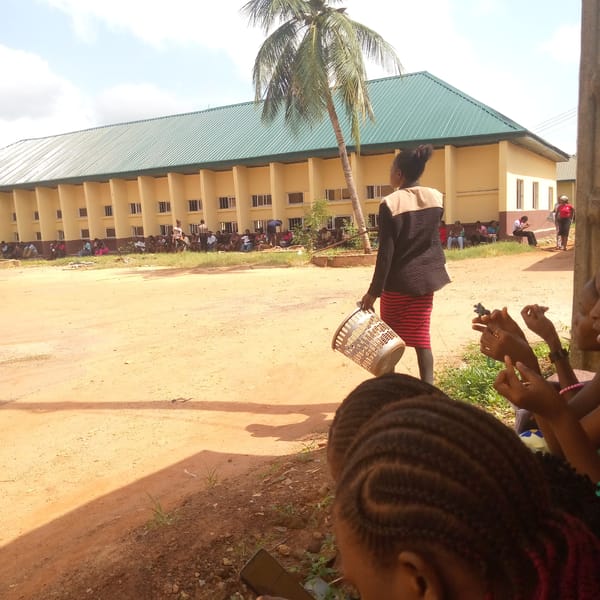 Women use smartphones outdoors near school in Ukwu-Abwa, Nigeria