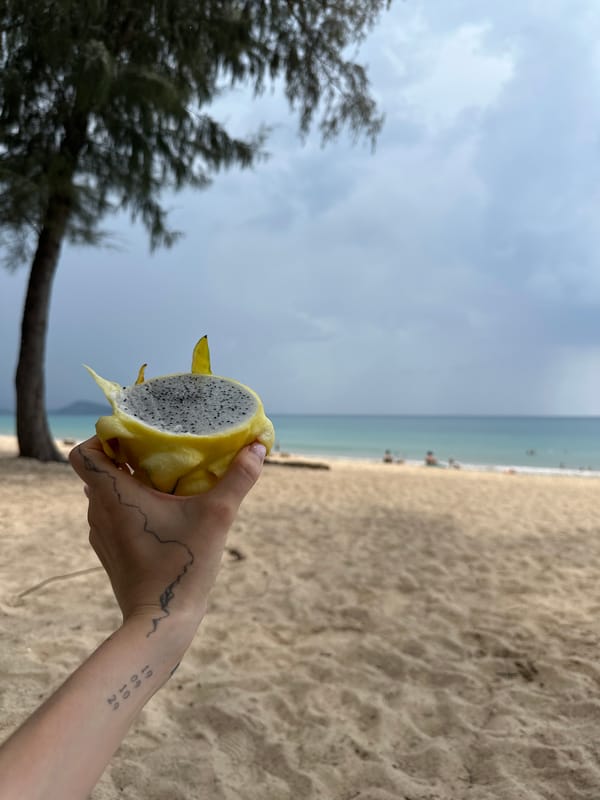 Person displays cut dragon fruit on Choeng Thale beach