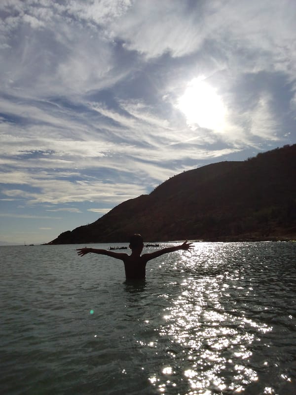 Sun-drenched ocean and hillside silhouettes, midday light