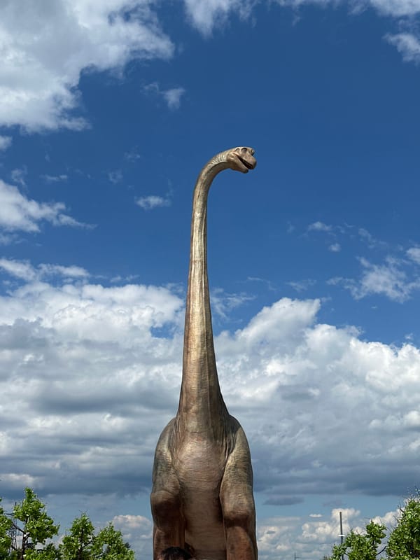 Sunny afternoon at an outdoor park with a dinosaur statue