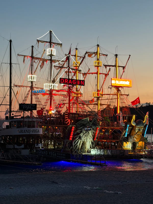 Illuminated tourist ships dock at Fethiye harbor during evening