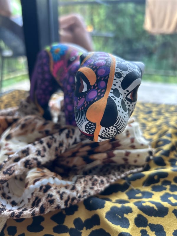Vibrant wooden cat sculpture spotted on patterned fabric in Thailand