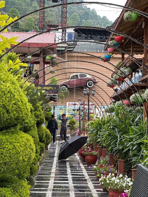 Pedestrians navigate rainy streets under archway in Pokhara