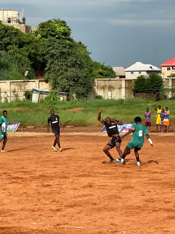 Community soccer match played on dirt field draws local spectators